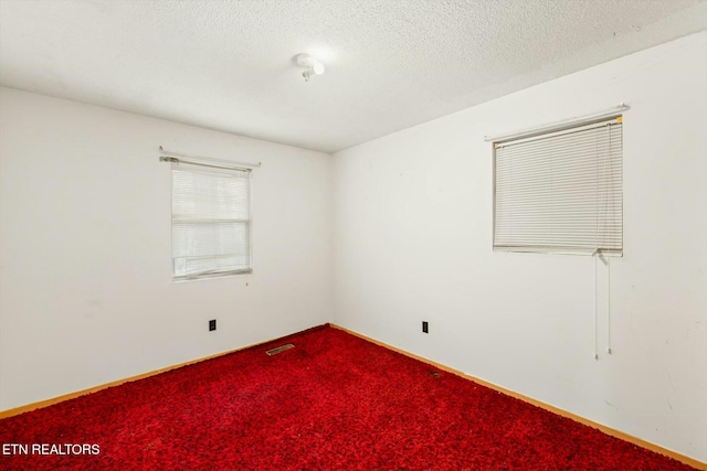 unfurnished room featuring carpet flooring and a textured ceiling