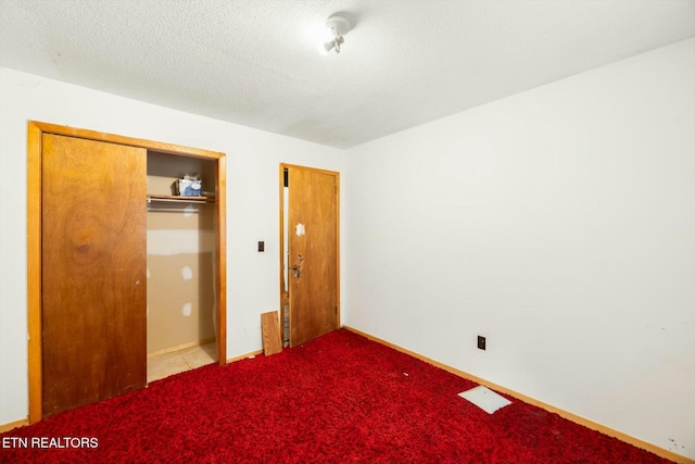 unfurnished bedroom featuring a textured ceiling, light colored carpet, and a closet