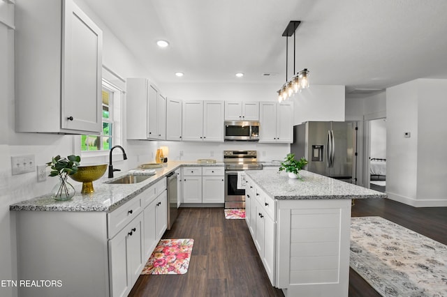 kitchen featuring pendant lighting, a center island, sink, appliances with stainless steel finishes, and dark hardwood / wood-style flooring