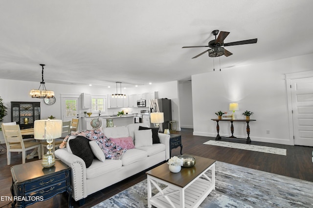 living room with dark wood-type flooring and ceiling fan with notable chandelier