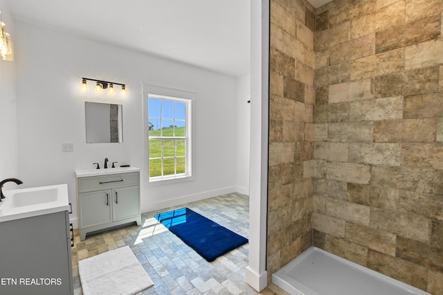 bathroom with a tile shower and vanity