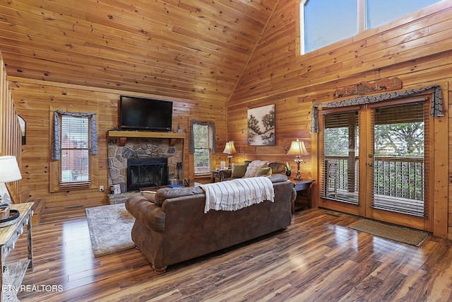 living room with wood walls, a healthy amount of sunlight, and high vaulted ceiling