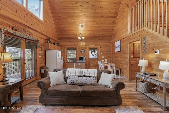 living room featuring a towering ceiling, a healthy amount of sunlight, and hardwood / wood-style flooring