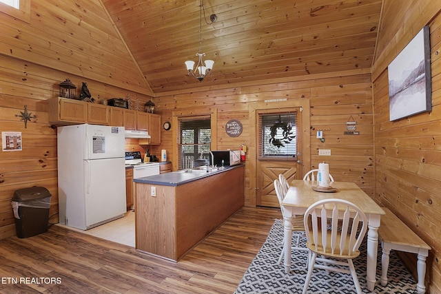 kitchen with light wood-type flooring, white appliances, wooden walls, pendant lighting, and high vaulted ceiling