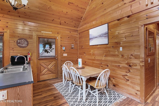 dining room featuring wood walls, dark hardwood / wood-style flooring, lofted ceiling, and sink