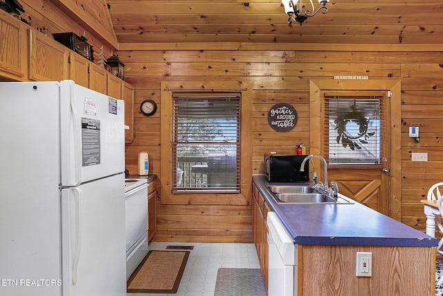 kitchen featuring sink, white appliances, wood walls, and an island with sink