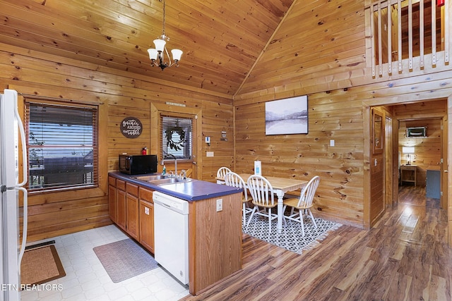 kitchen with wood walls, white appliances, sink, and high vaulted ceiling