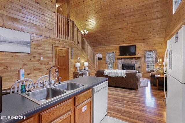 kitchen featuring white appliances, wooden walls, sink, light hardwood / wood-style flooring, and high vaulted ceiling