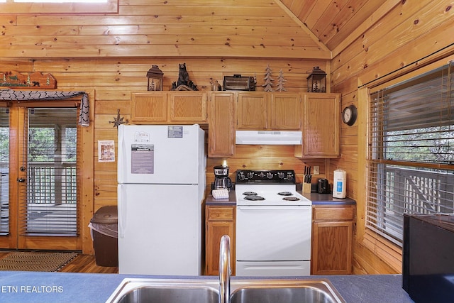 kitchen featuring white appliances, sink, hardwood / wood-style floors, lofted ceiling, and wood walls