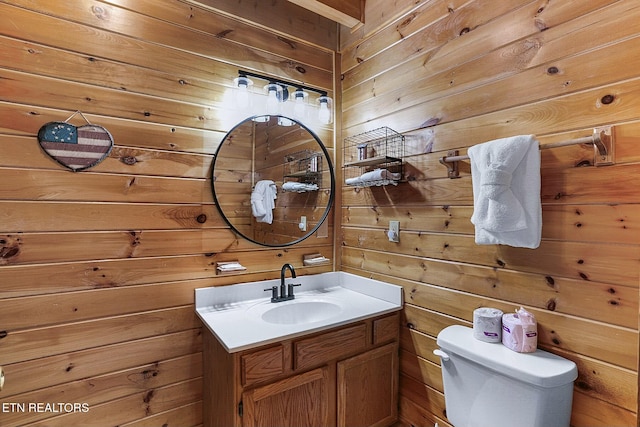 bathroom with vanity, toilet, and wooden walls