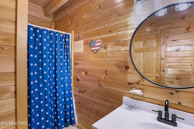 bathroom featuring a shower with shower curtain, sink, and wood walls