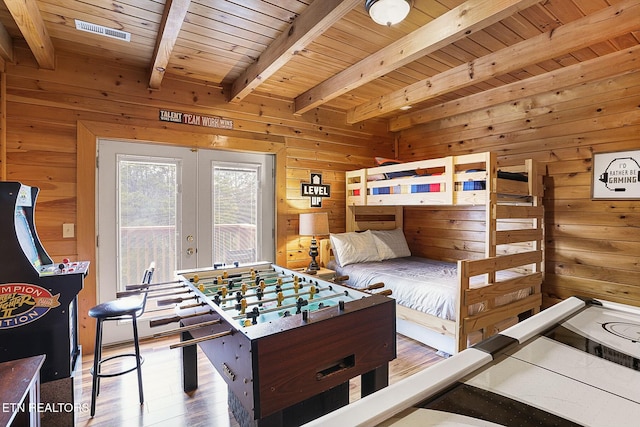 bedroom featuring french doors, wood-type flooring, beam ceiling, wooden ceiling, and wood walls