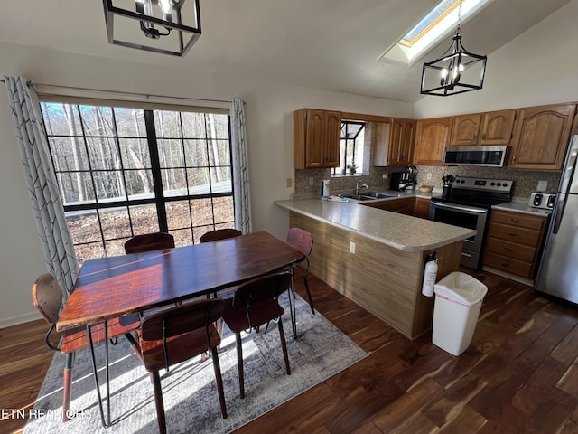 kitchen with sink, hanging light fixtures, backsplash, kitchen peninsula, and appliances with stainless steel finishes