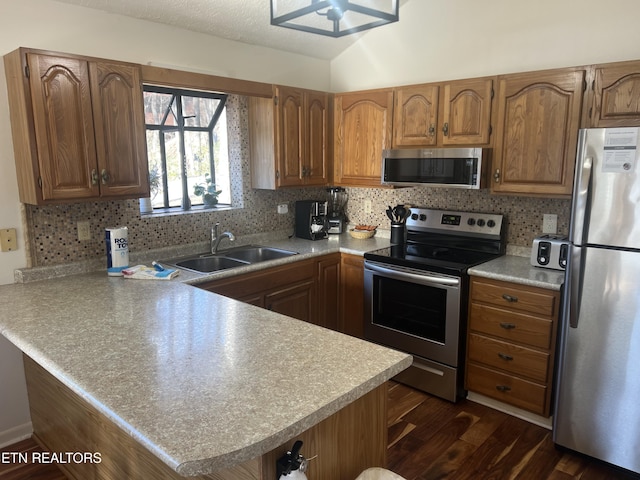 kitchen with kitchen peninsula, appliances with stainless steel finishes, backsplash, and sink