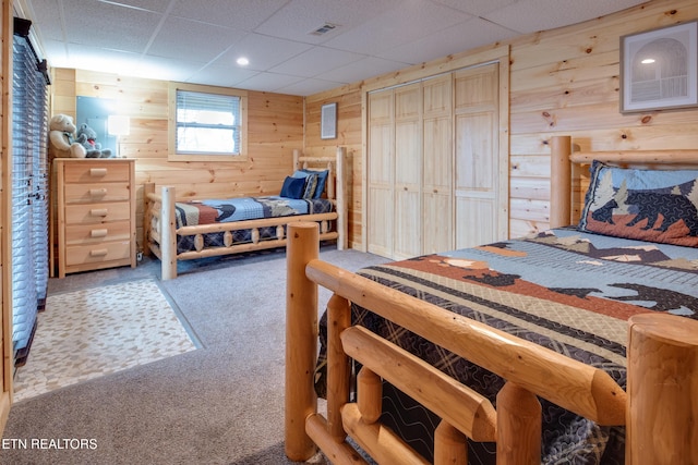 bedroom featuring wood walls, carpet floors, and a closet