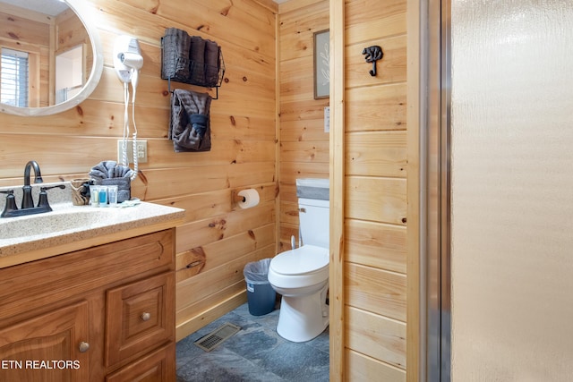 bathroom with vanity, toilet, and wood walls