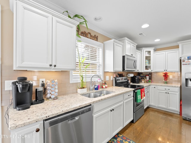 kitchen featuring white cabinets, sink, light wood-type flooring, ornamental molding, and stainless steel appliances