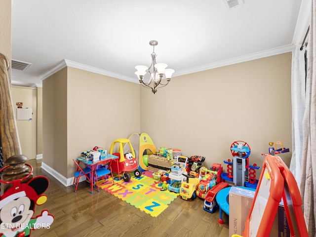 recreation room featuring hardwood / wood-style floors, a notable chandelier, and ornamental molding