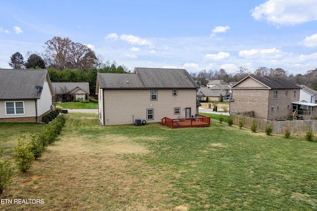 rear view of property featuring a lawn, a deck, and central AC