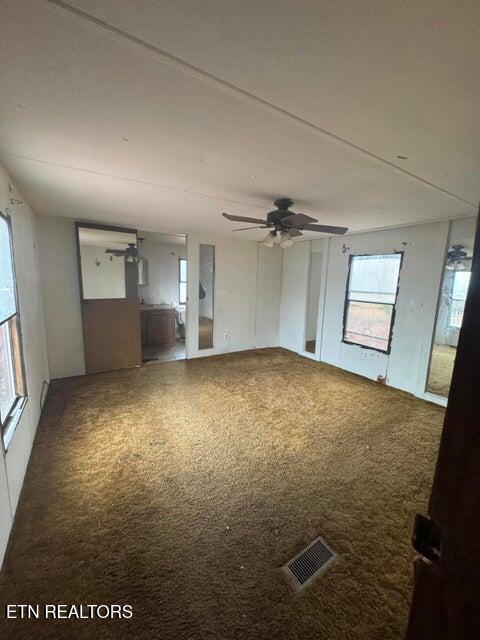 unfurnished living room featuring carpet flooring and ceiling fan