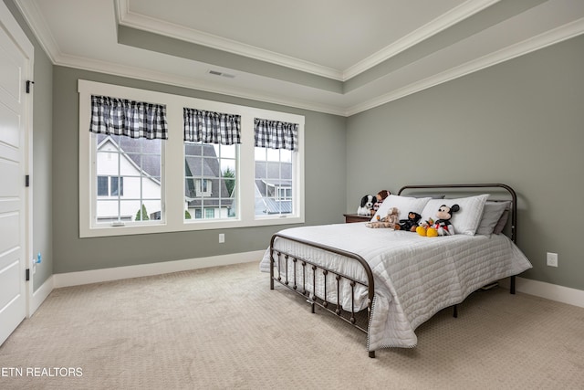 carpeted bedroom with a tray ceiling, multiple windows, and crown molding