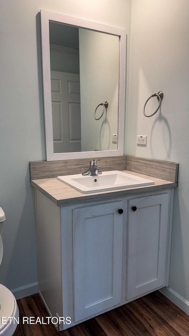 bathroom with wood-type flooring, vanity, and toilet