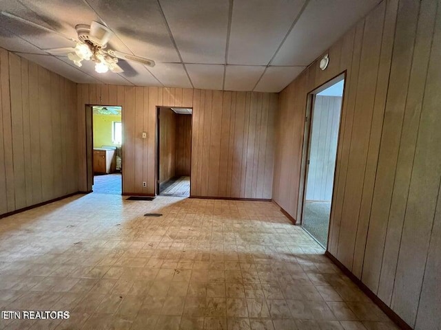 unfurnished room with ceiling fan and wood walls