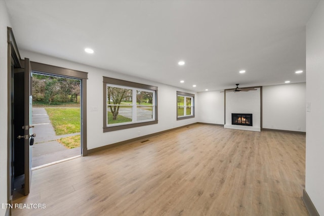 unfurnished living room featuring ceiling fan, light hardwood / wood-style flooring, and a brick fireplace