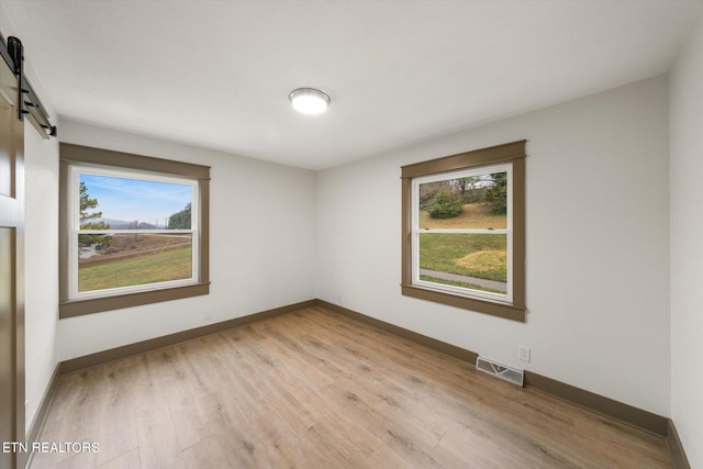 spare room with light wood-type flooring and a barn door