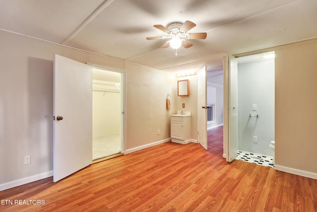 unfurnished bedroom featuring ensuite bathroom, ceiling fan, sink, and light hardwood / wood-style flooring