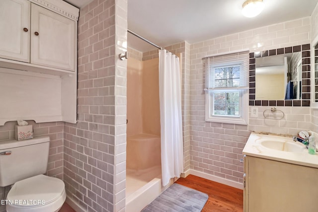 bathroom featuring hardwood / wood-style flooring, toilet, tile walls, and curtained shower