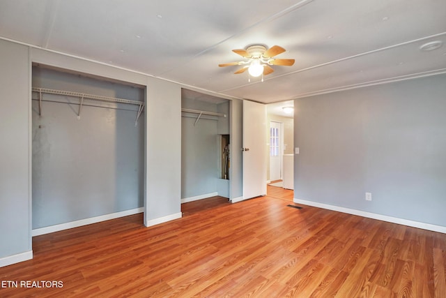 unfurnished bedroom with light wood-type flooring, ceiling fan, and multiple closets