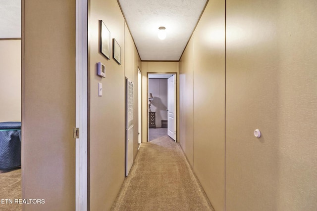 corridor with a textured ceiling and light carpet