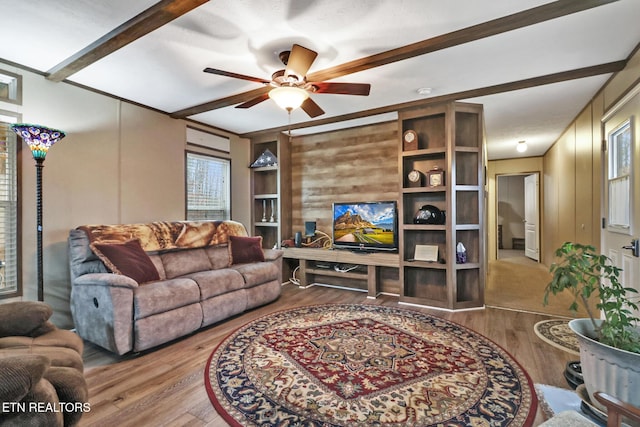 living room featuring hardwood / wood-style floors, ceiling fan, and beamed ceiling