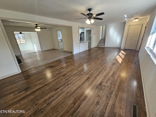 unfurnished living room featuring ceiling fan, plenty of natural light, and dark hardwood / wood-style floors