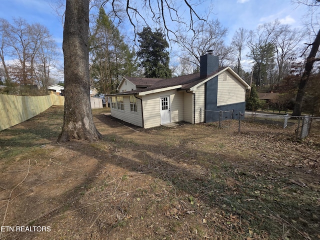 rear view of property with a chimney and fence