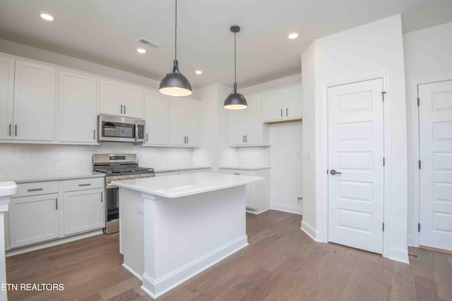 kitchen with white cabinetry, a center island, pendant lighting, stainless steel appliances, and hardwood / wood-style floors