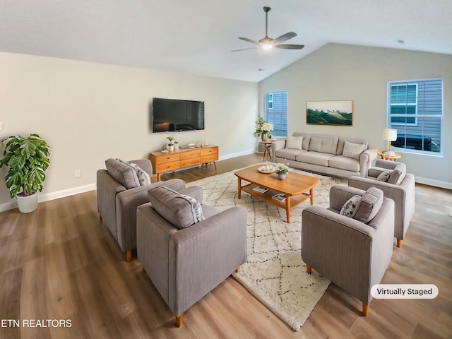 living room featuring a wealth of natural light, ceiling fan, wood-type flooring, and vaulted ceiling