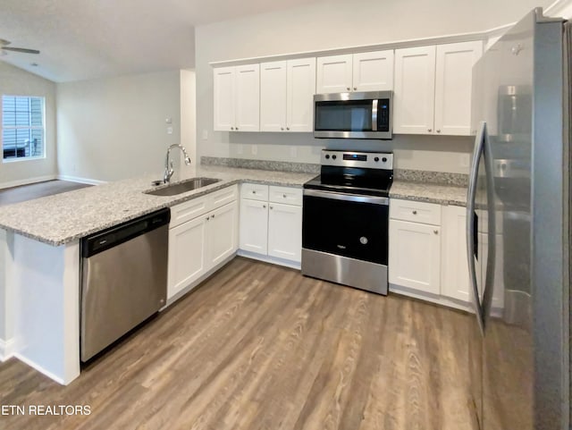 kitchen featuring kitchen peninsula, appliances with stainless steel finishes, light stone counters, sink, and white cabinetry