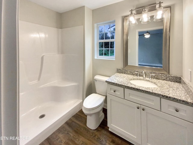 bathroom featuring ceiling fan, walk in shower, toilet, vanity, and hardwood / wood-style flooring