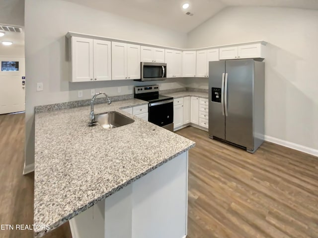 kitchen featuring kitchen peninsula, stainless steel appliances, vaulted ceiling, and sink