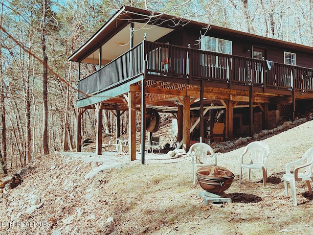 rear view of property featuring a fire pit and a wooden deck