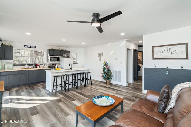 living room with ceiling fan, wood-type flooring, and sink