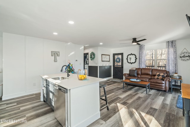 kitchen featuring sink, light hardwood / wood-style flooring, stainless steel dishwasher, and an island with sink