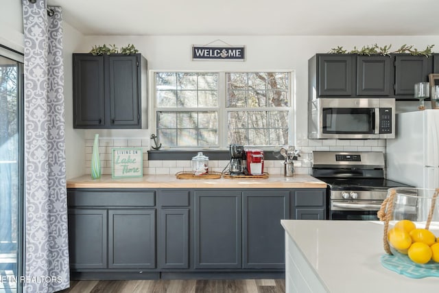 kitchen with decorative backsplash, appliances with stainless steel finishes, dark hardwood / wood-style flooring, and gray cabinets