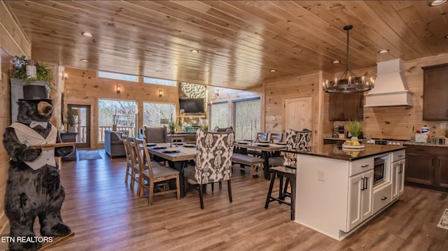 dining space with wood walls, an inviting chandelier, hardwood / wood-style flooring, a fireplace, and wood ceiling