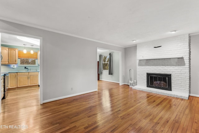 unfurnished living room featuring light hardwood / wood-style floors, sink, ornamental molding, and a fireplace