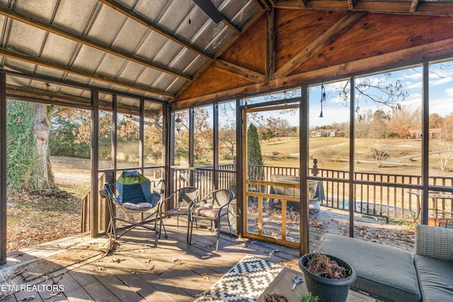 unfurnished sunroom featuring a rural view, vaulted ceiling, and a wealth of natural light