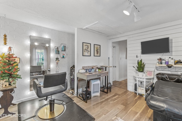 home office with a textured ceiling, track lighting, and light wood-type flooring