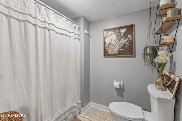 bathroom featuring tile patterned floors, toilet, and a textured ceiling